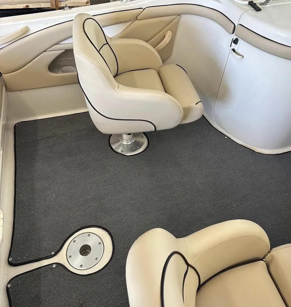The inside of a boat with two chairs and a steering wheel