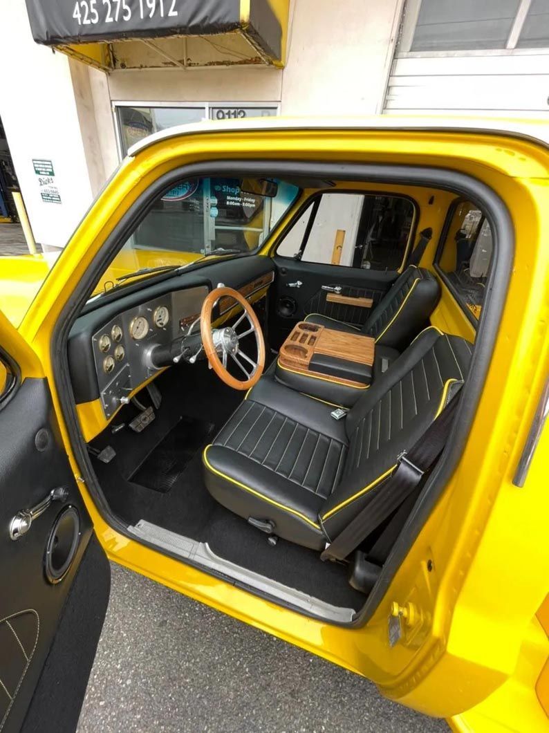 A yellow truck with black seats and a wooden steering wheel