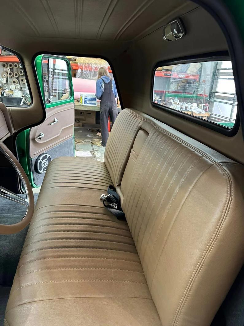 A man is standing in the back seat of a green truck.