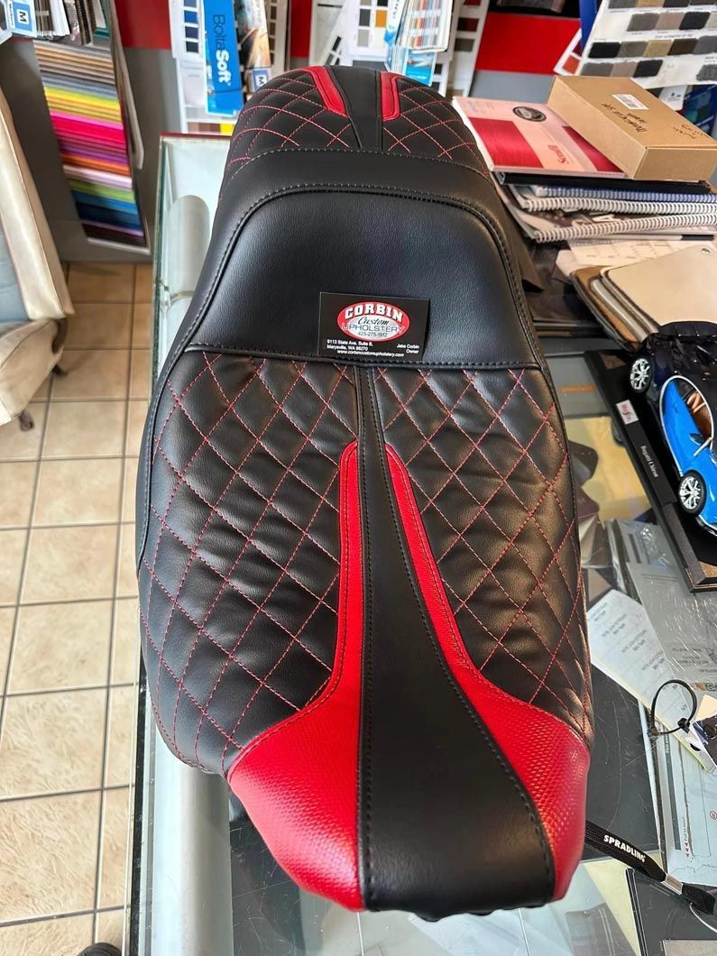 A black and red motorcycle seat cover is sitting on a glass table.