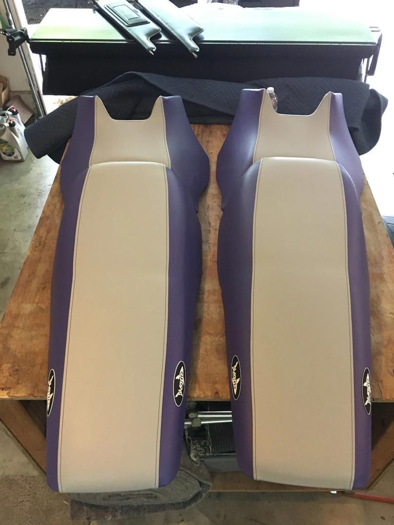 A pair of purple and white seats are sitting on top of a wooden table.