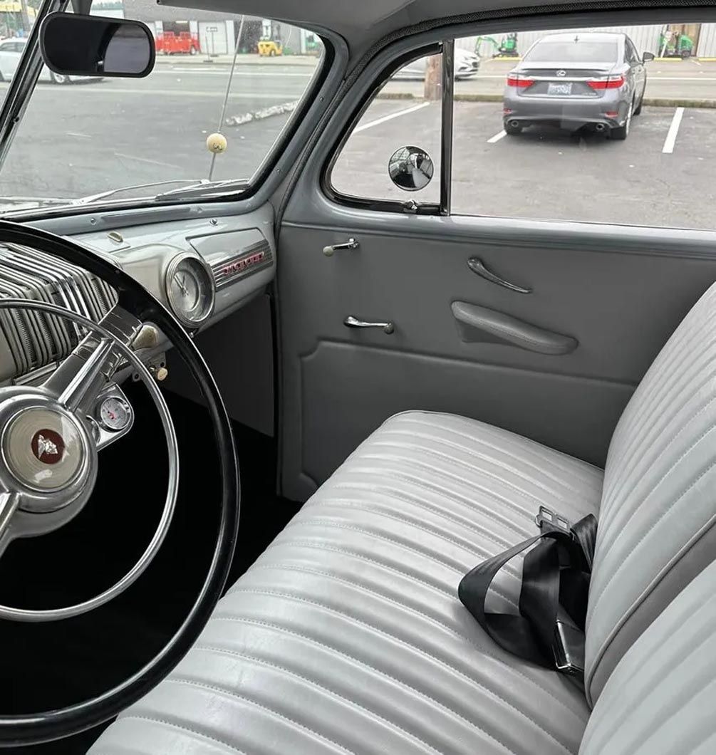 The inside of an old car with a steering wheel and seats