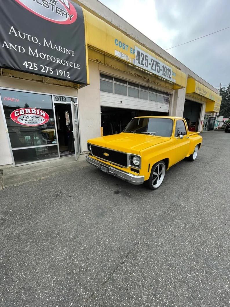 A yellow car is parked in front of a building.