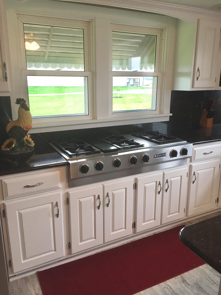 a kitchen with white cabinets and a stove top oven