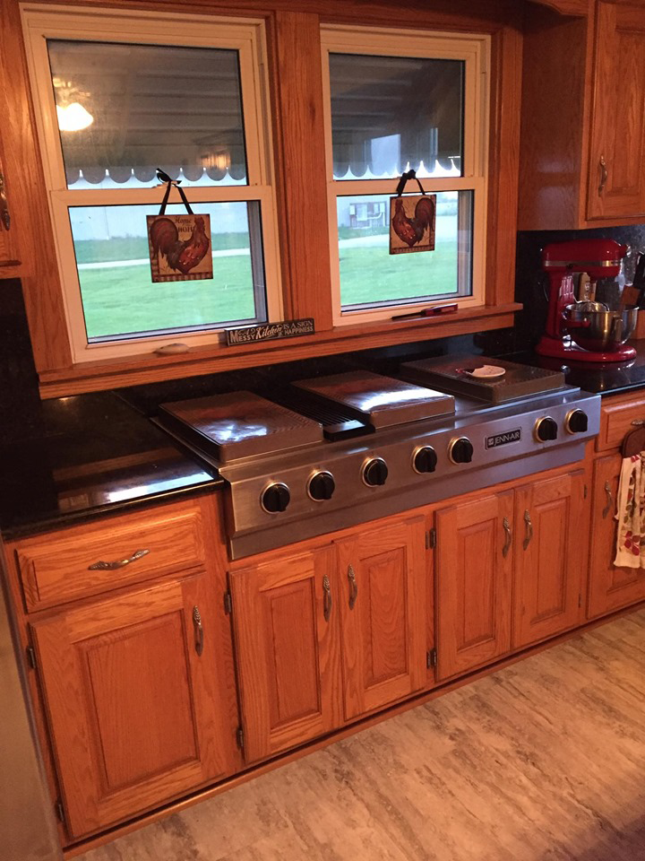 a kitchen with wooden cabinets , a stove , and a window .