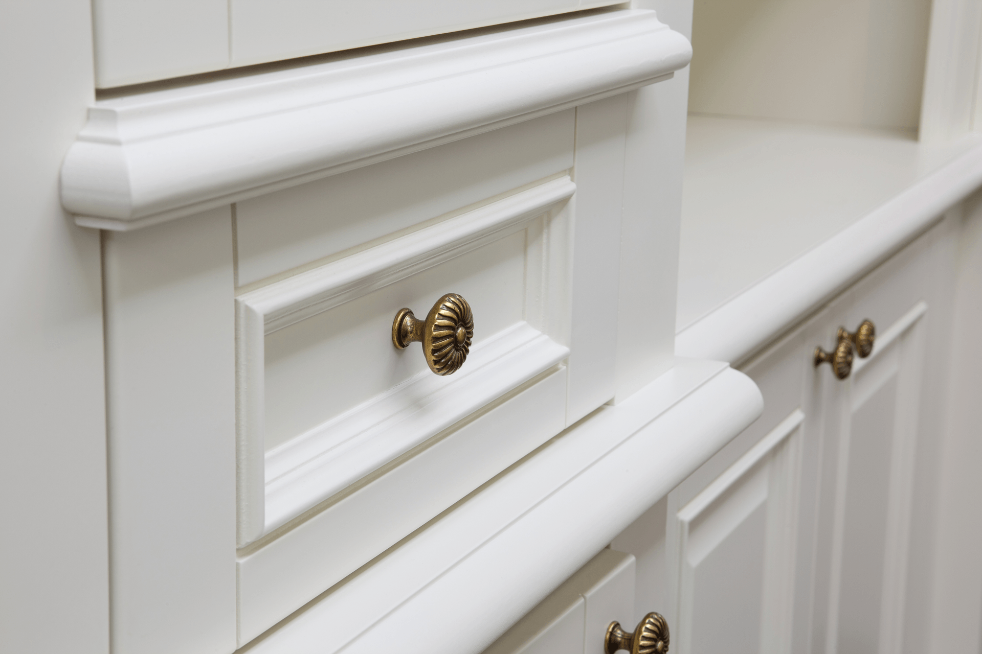 a close up of a white cabinet with gold knobs
