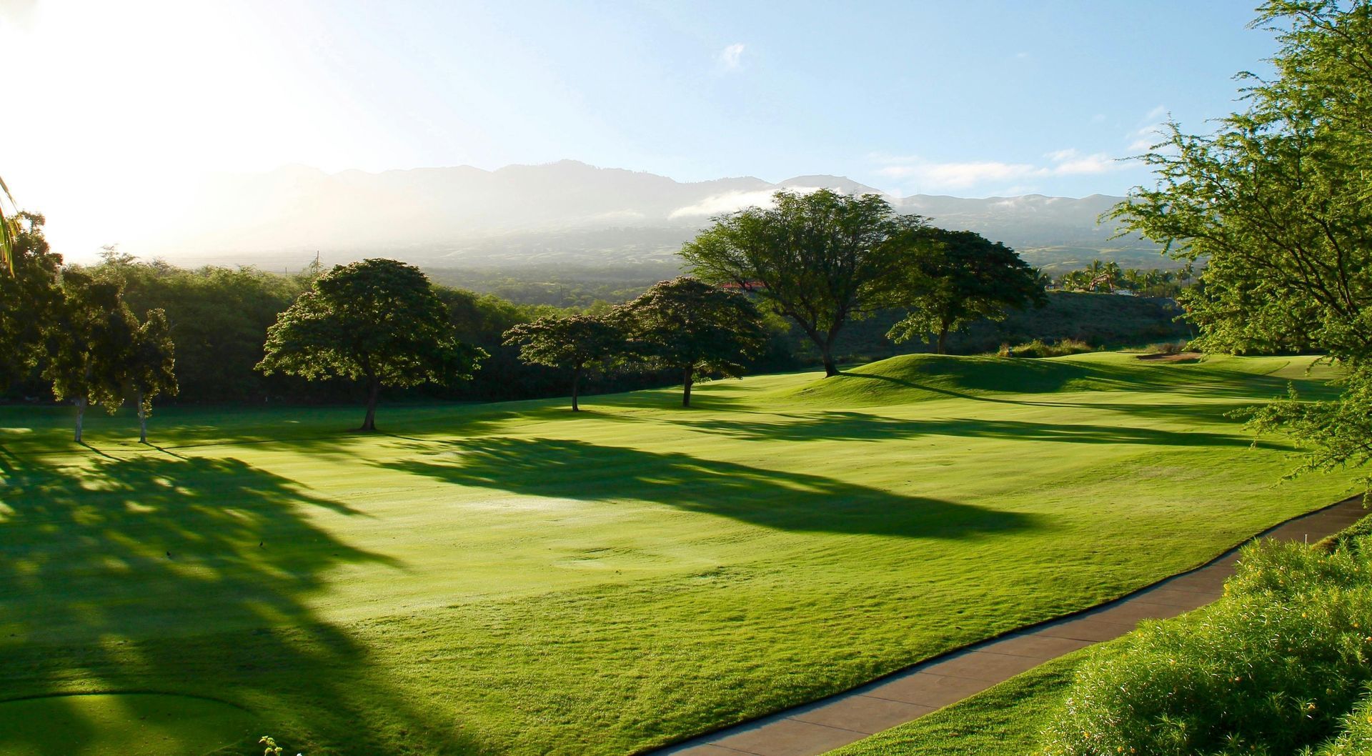 A golf course with trees and mountains in the background