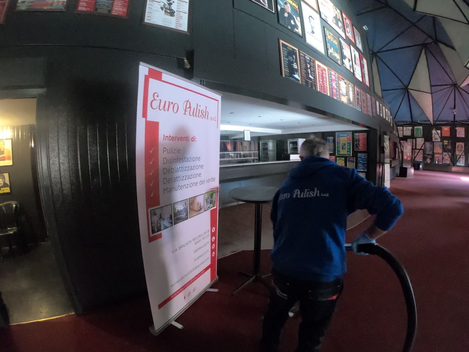 Un uomo con una felpa blu sistema un cartello con la scritta 