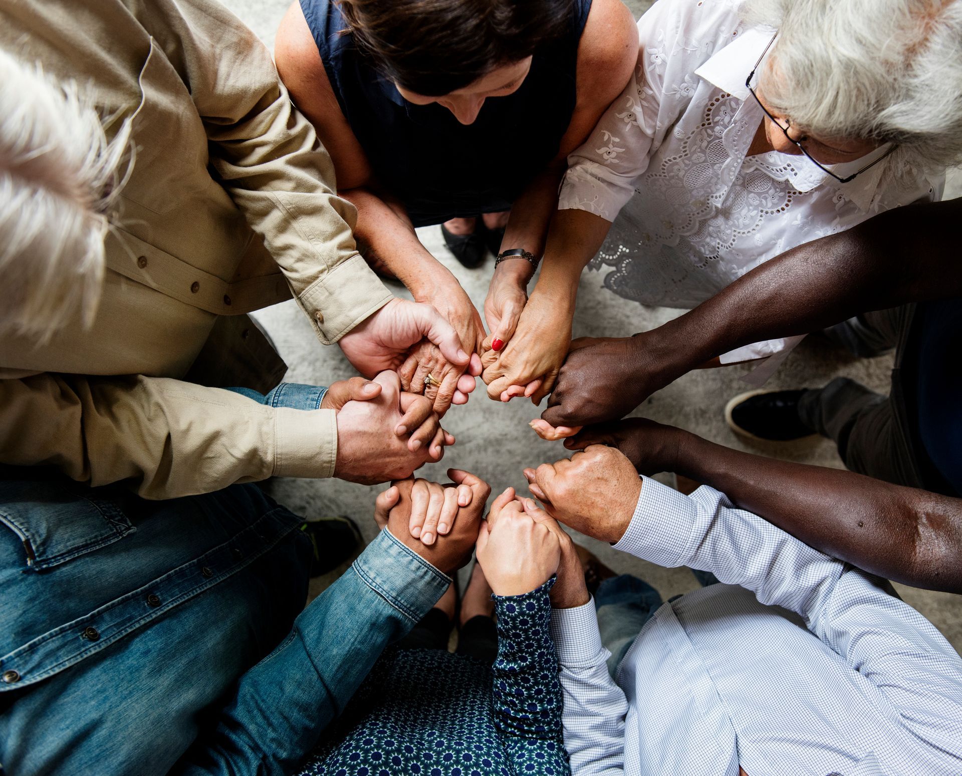 A group of people are sitting in a circle holding hands.