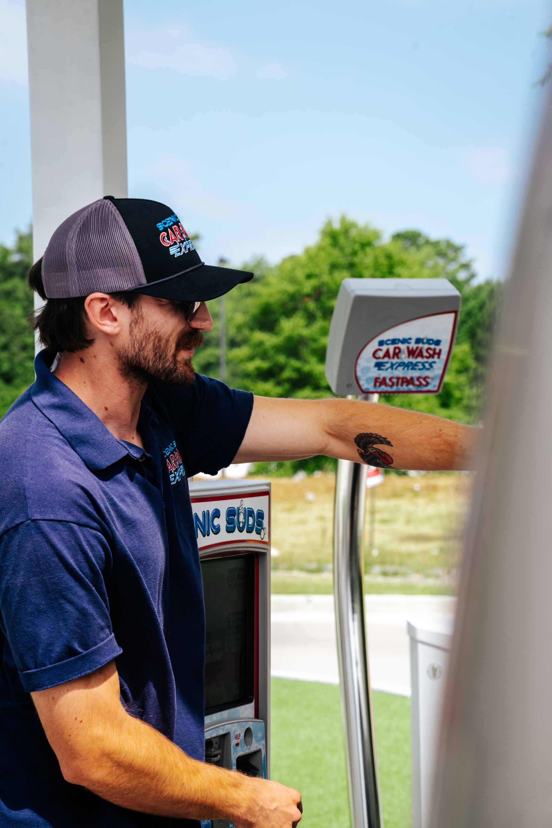 A man is standing in front of a car wash machine.