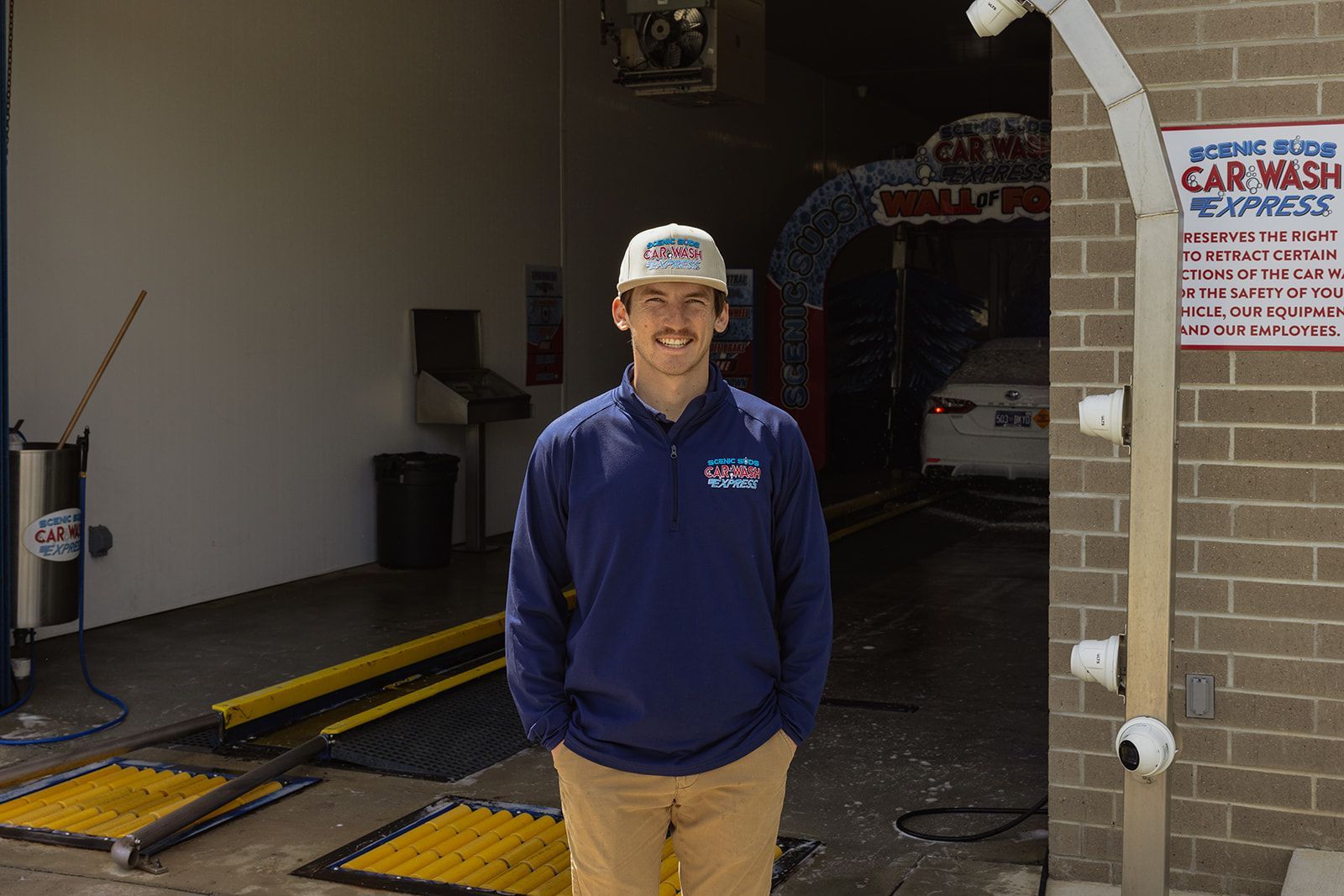 A man is standing in front of a car wash.