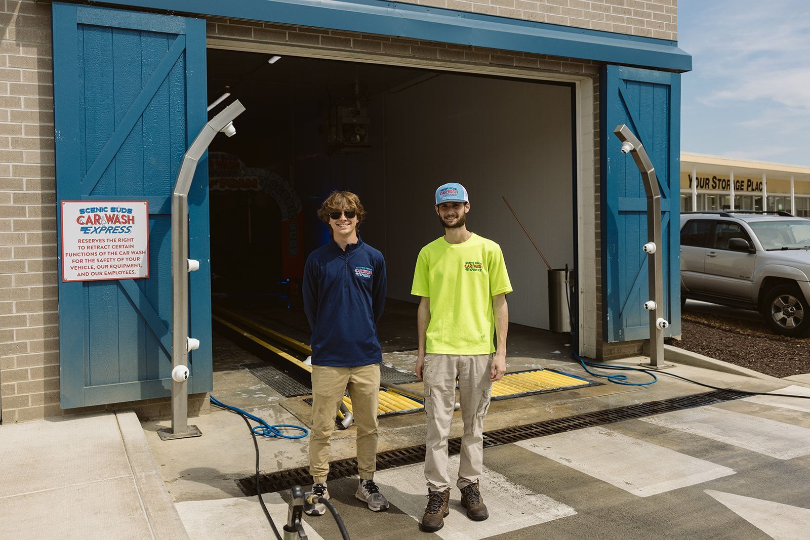 Two men are standing in front of a car wash.