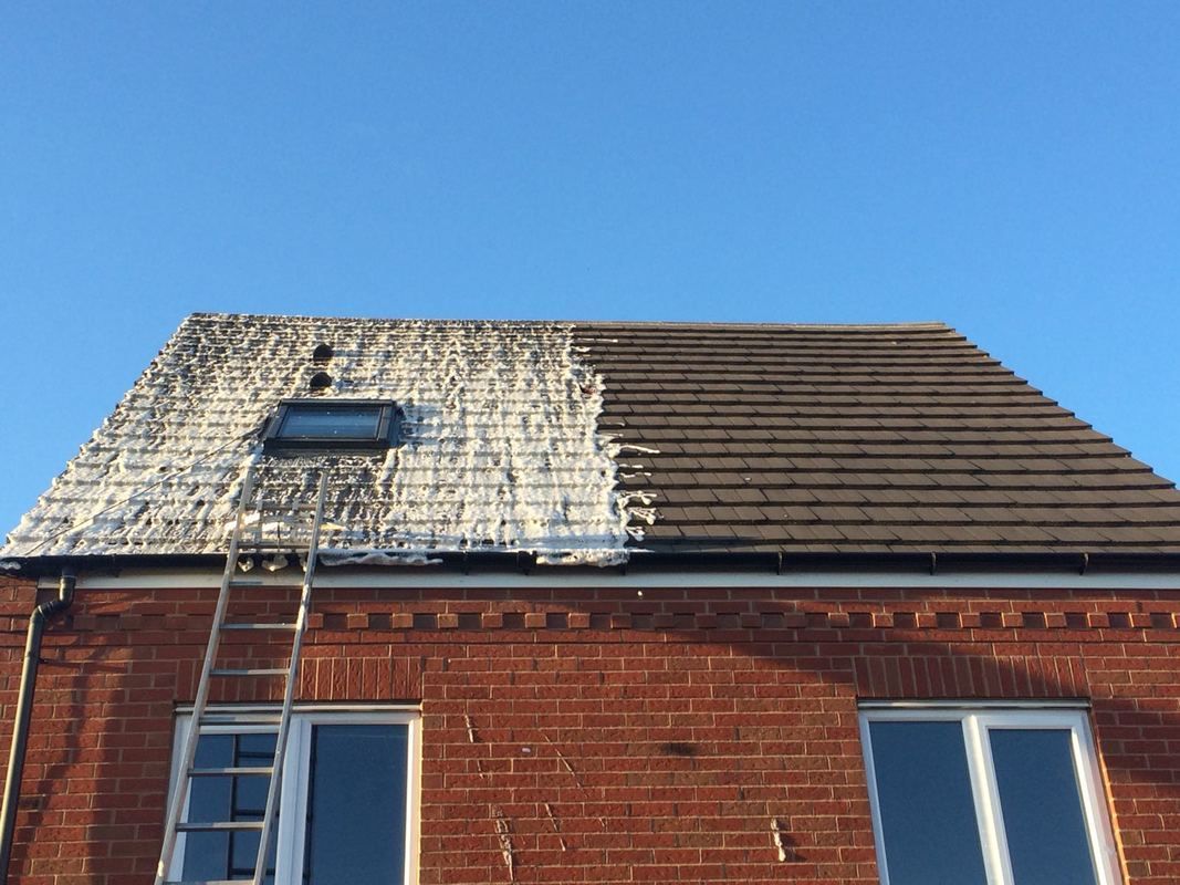 A ladder is sitting on the roof of a brick house.