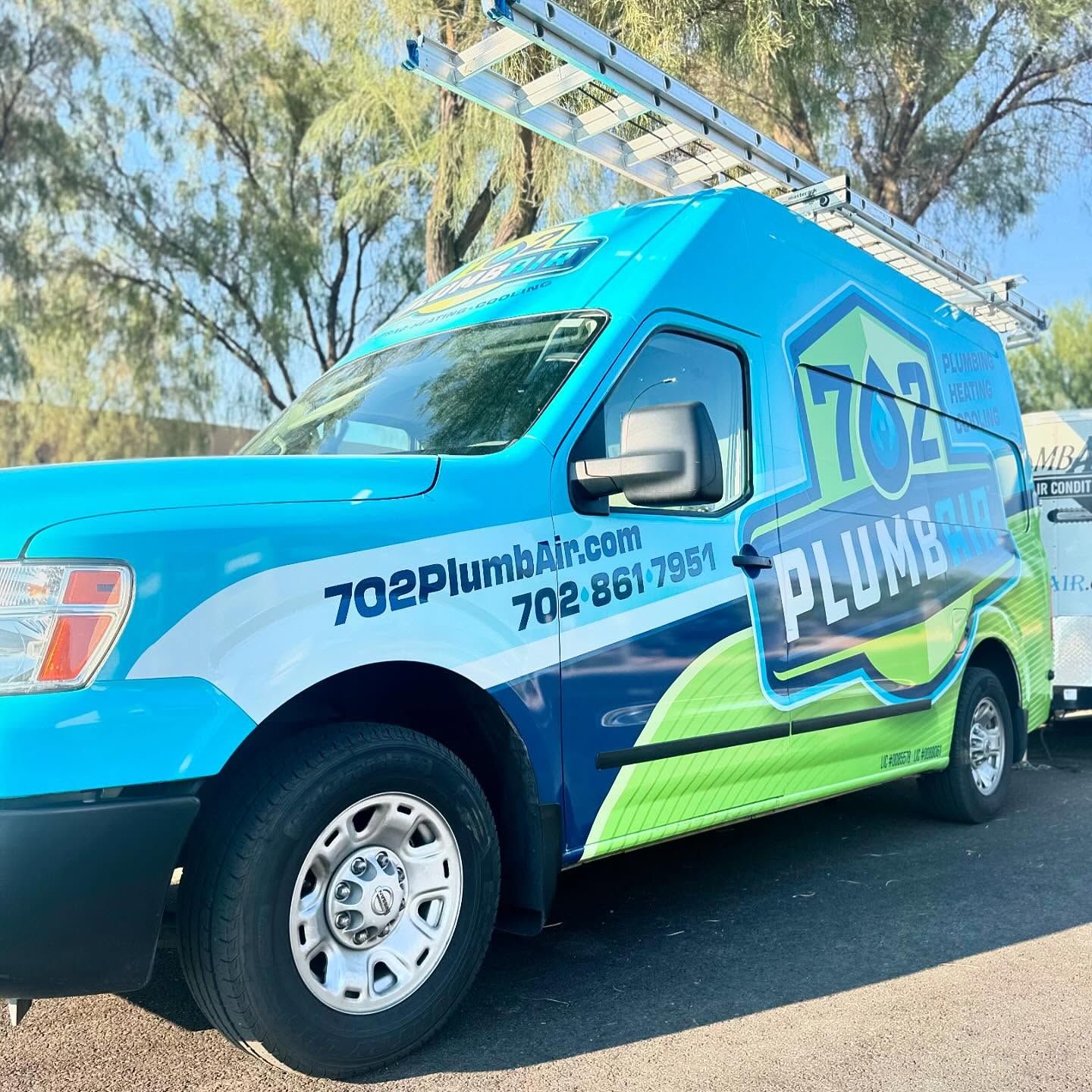 A blue and green plumbing van is parked on the side of the road.