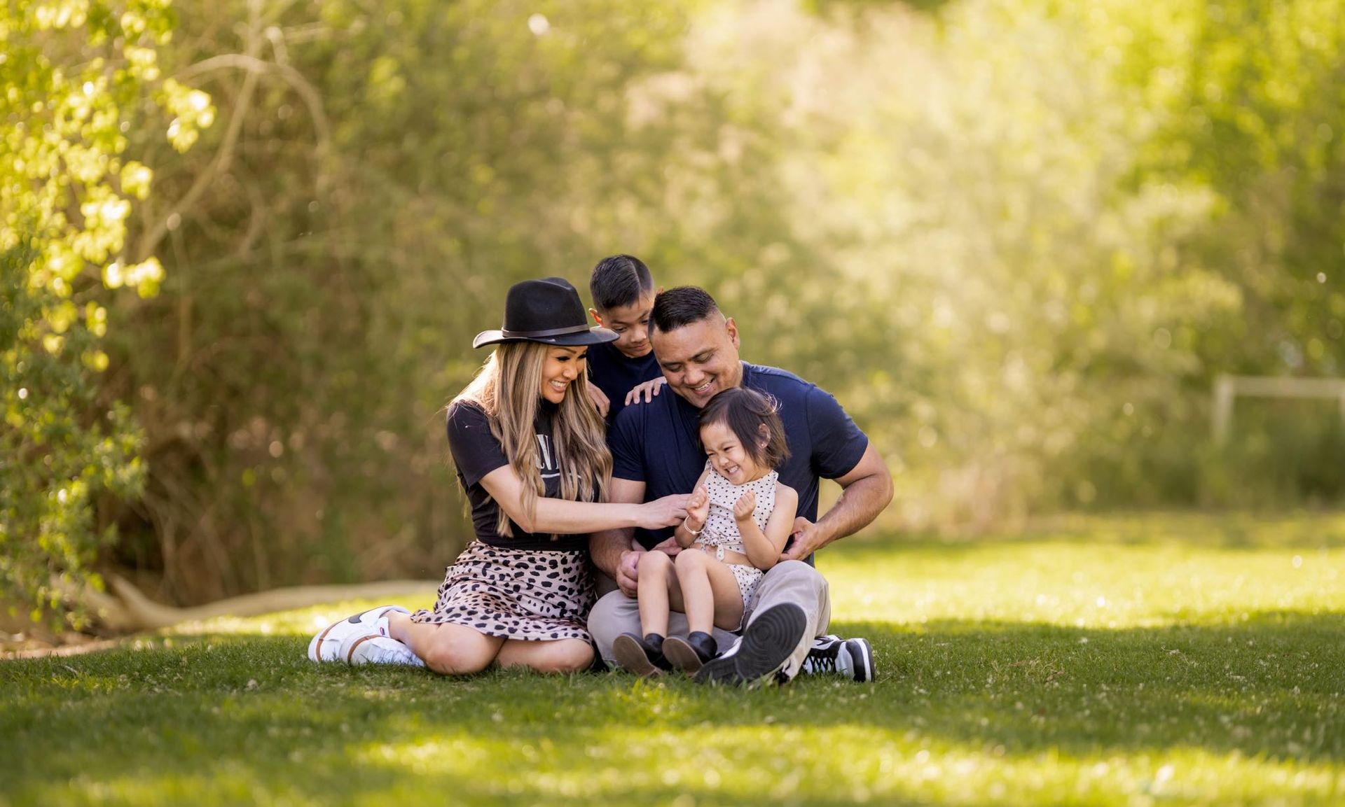 A family is sitting on the grass in a park.