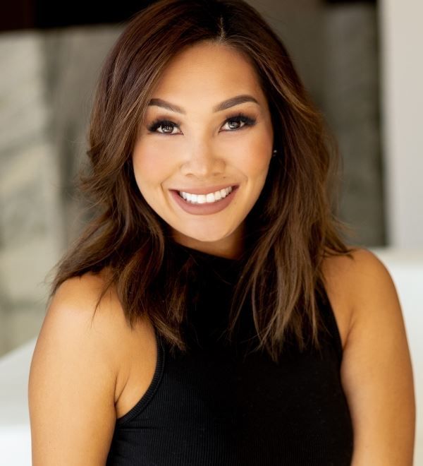 A woman in a black tank top is smiling for the camera.