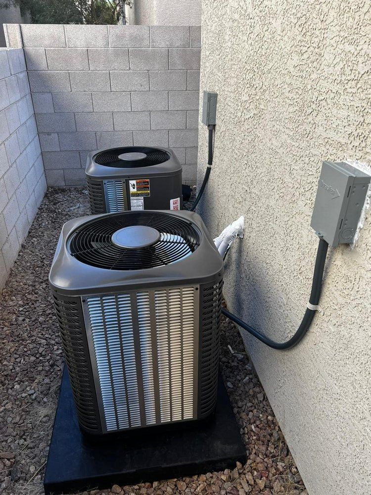 Two air conditioners are sitting next to each other on the side of a building.