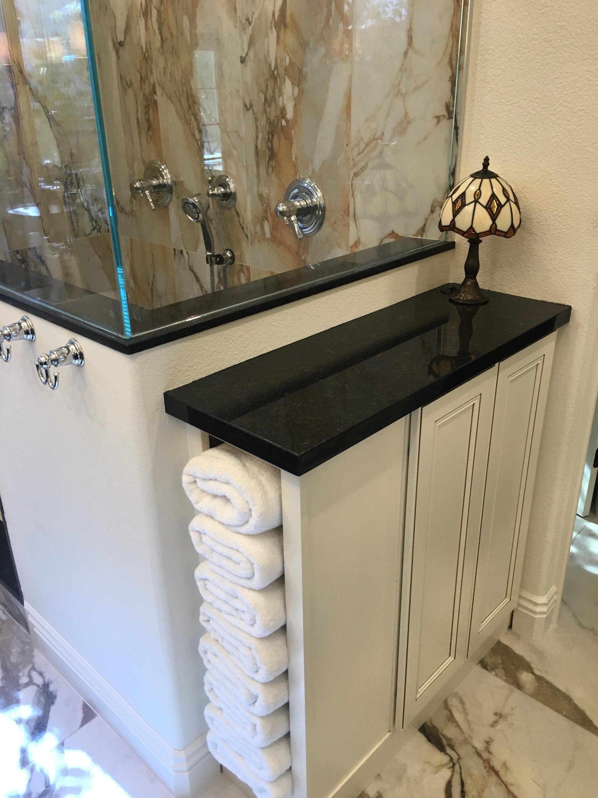 A bathroom with a sink , towels , and a lamp.