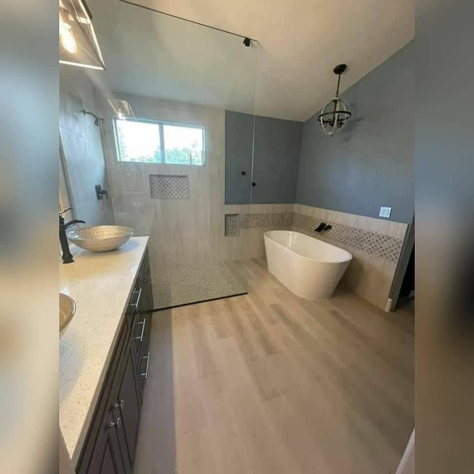 A bathroom with a tub , sink , and walk in shower.