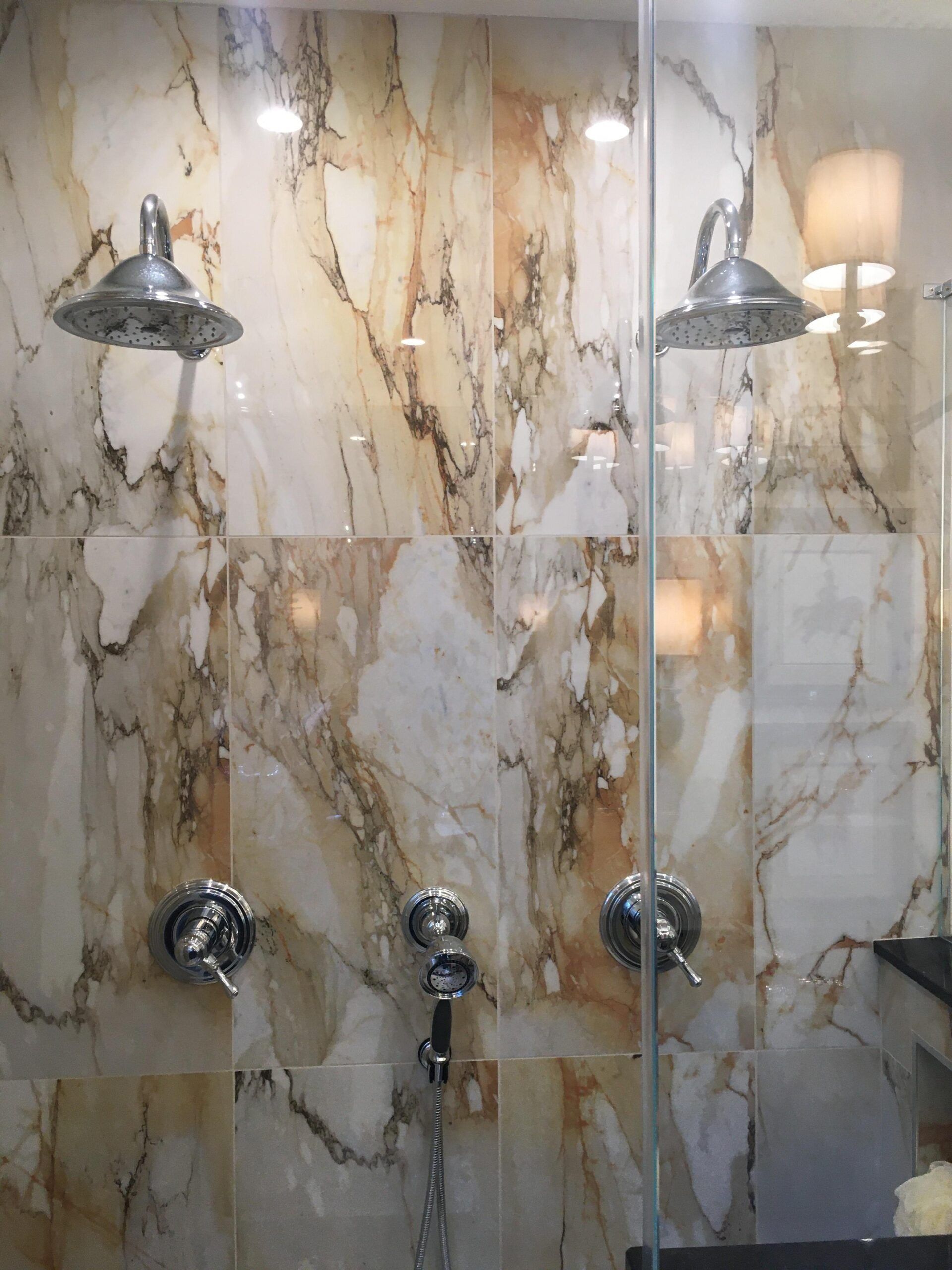A bathroom with marble tiles and two shower heads.