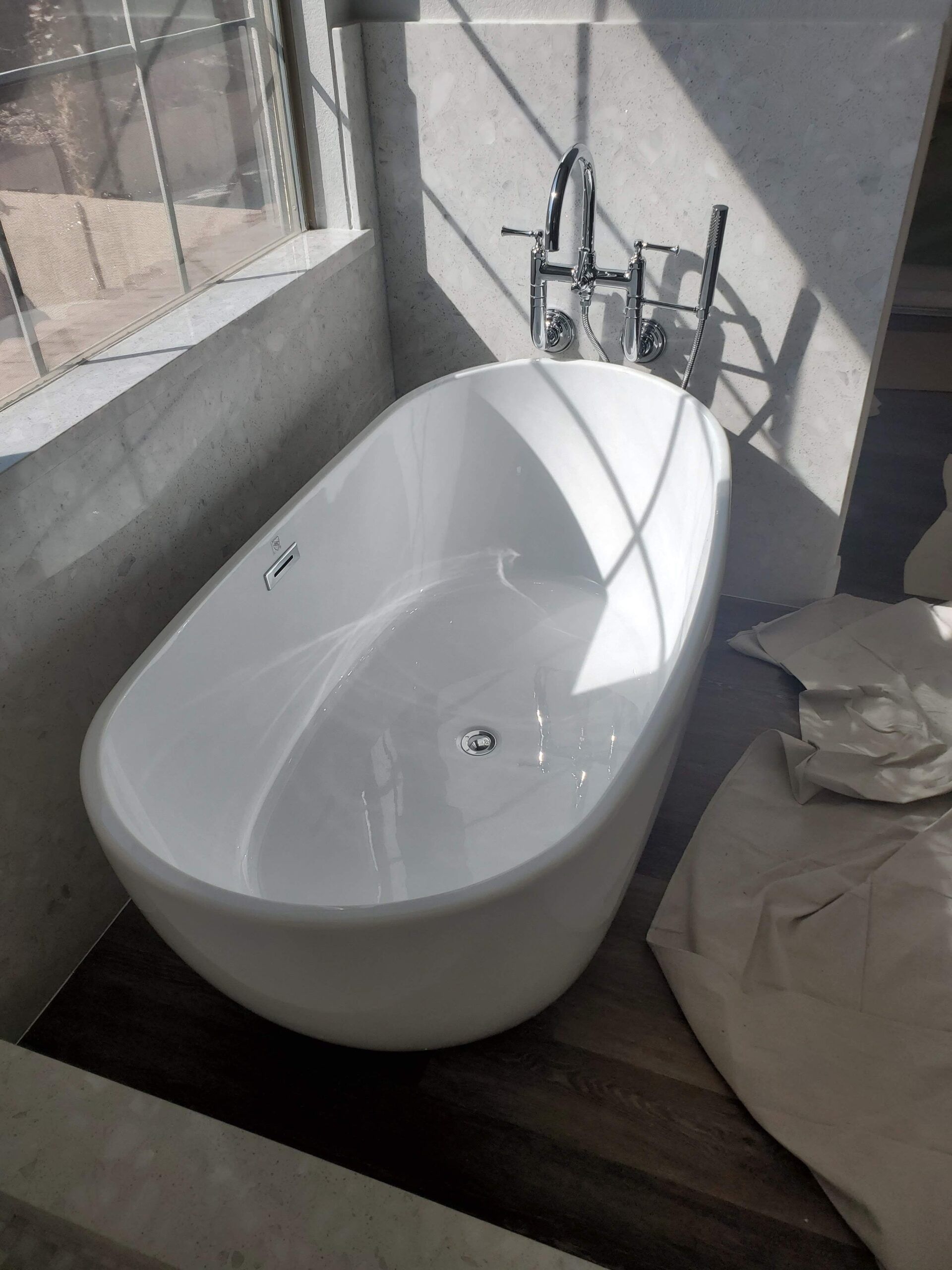 A white bathtub is sitting in a bathroom next to a window.