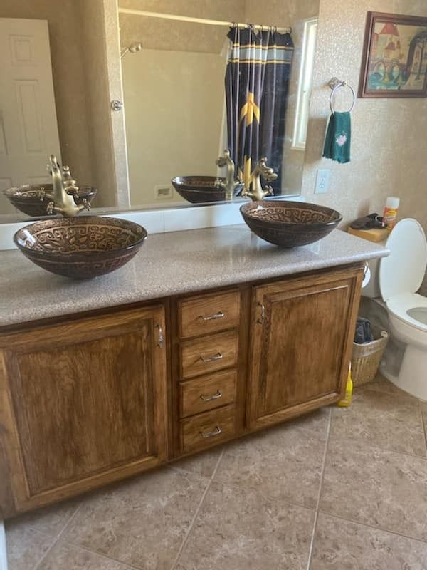 A bathroom with two sinks , a toilet and a mirror.