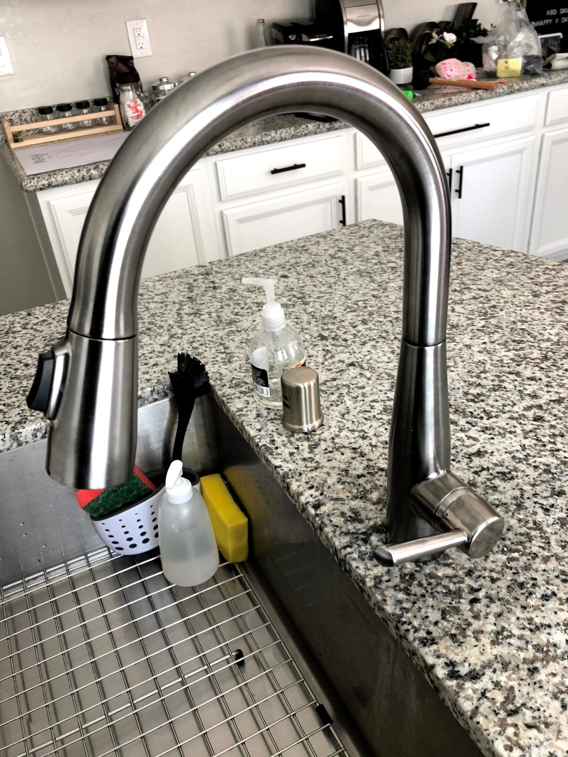 A kitchen sink with a stainless steel faucet on a granite counter top.