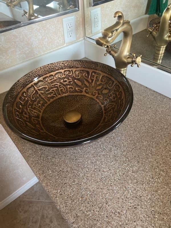 A bathroom sink with a brass faucet and a mirror