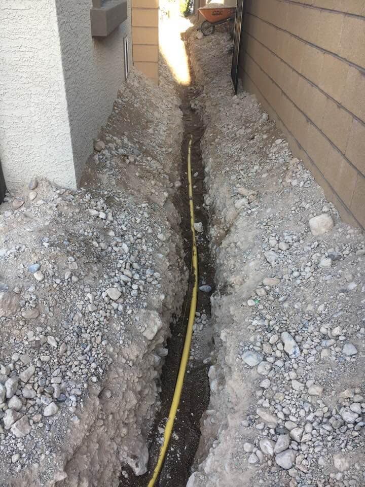 A yellow hose is laying in the dirt next to a house