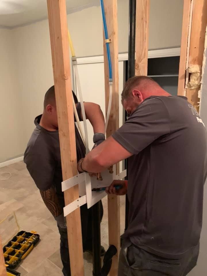 Two men are working on a wooden structure in a room