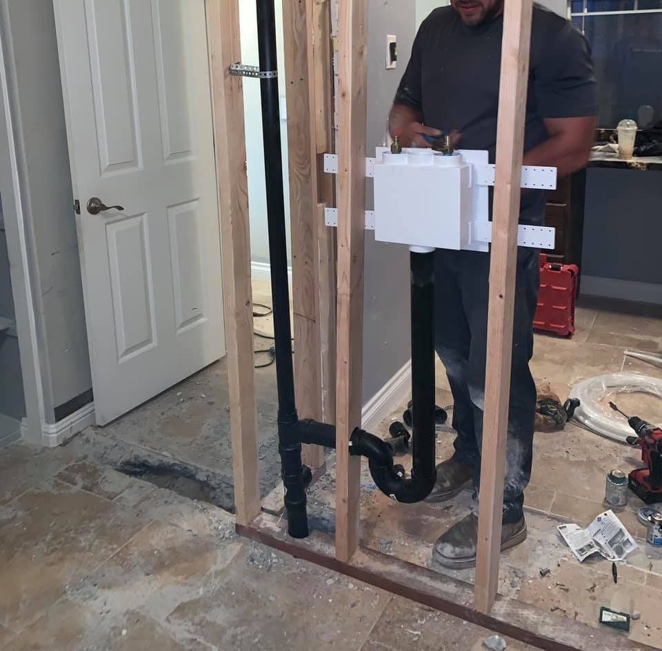 A man in a gray shirt is working on a wall