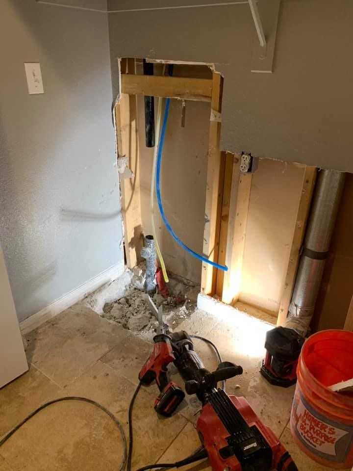 A room with a hole in the wall and a bucket of bleach on the floor.