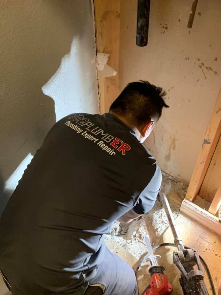A man in a plumber shirt is kneeling down in a room.