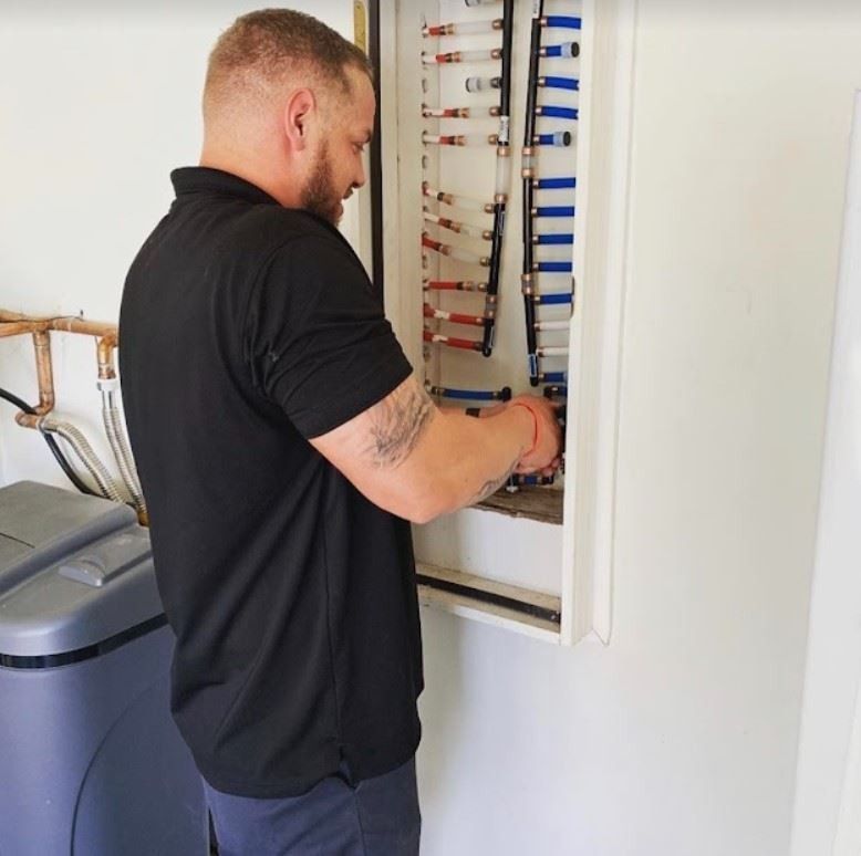 A man in a black shirt is working on an electrical box