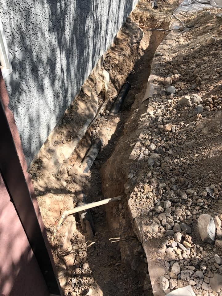 A person is digging a hole in the ground next to a fence.