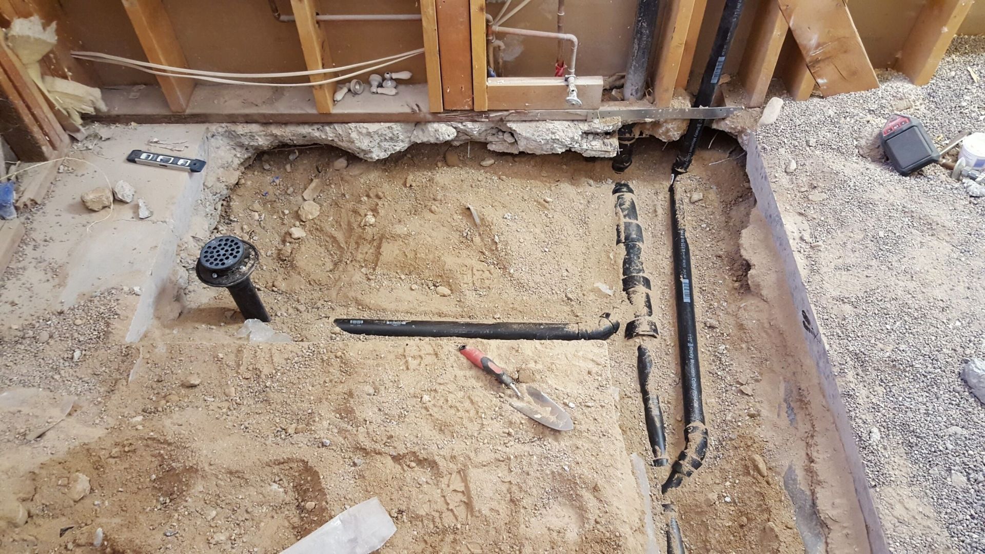 A bathroom under construction with a lot of pipes in the dirt.