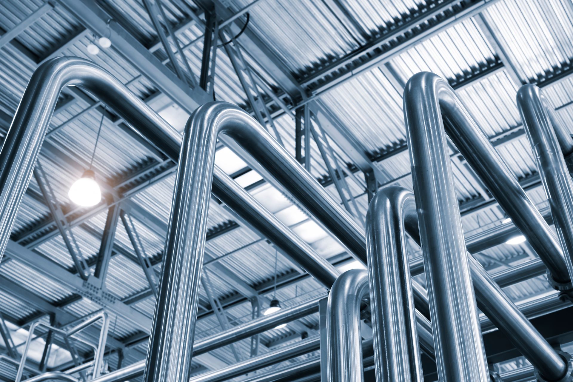 A bunch of metal pipes are hanging from the ceiling of a building.