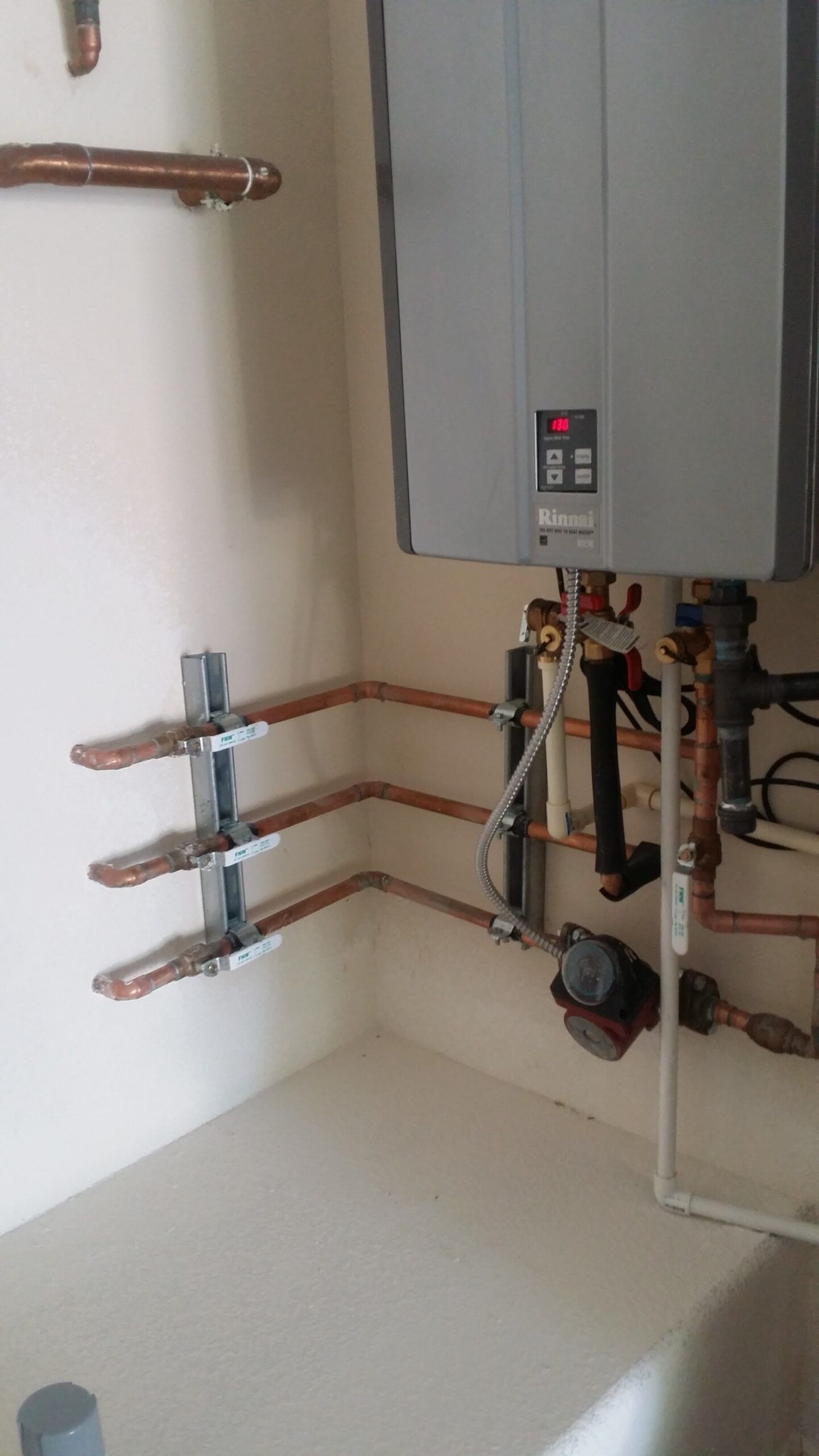 A bathroom with a water heater and copper pipes.