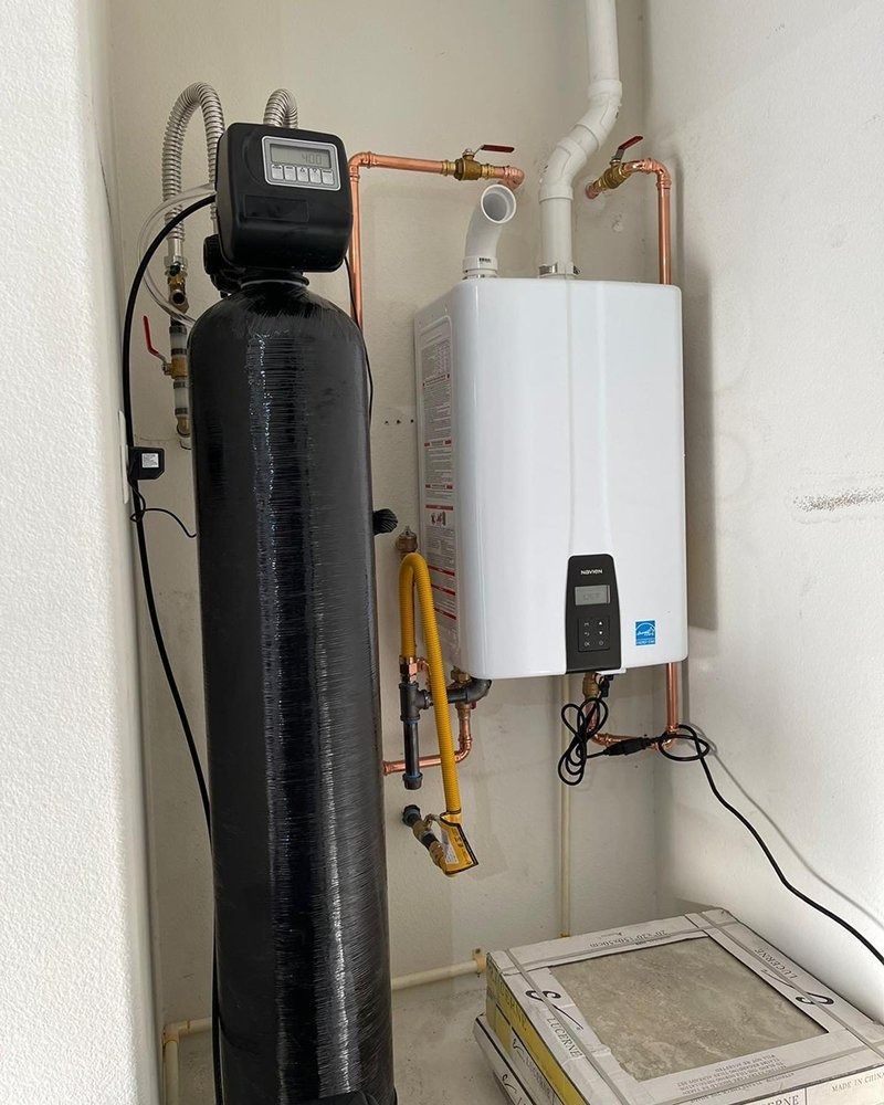 A water filter is sitting next to a water heater in a room.