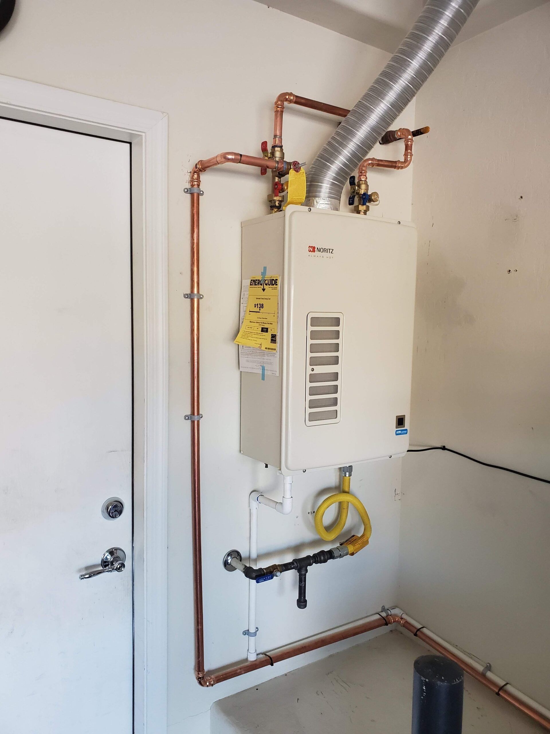 A water heater is hanging on a wall next to a door.