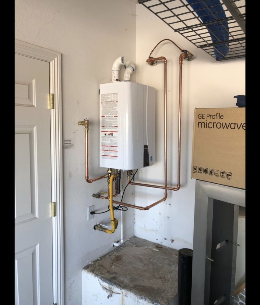 A water heater is mounted to a wall next to a box that says microwave