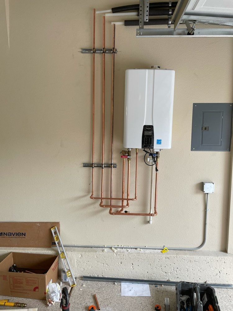 A water heater is being installed on a wall in a garage.