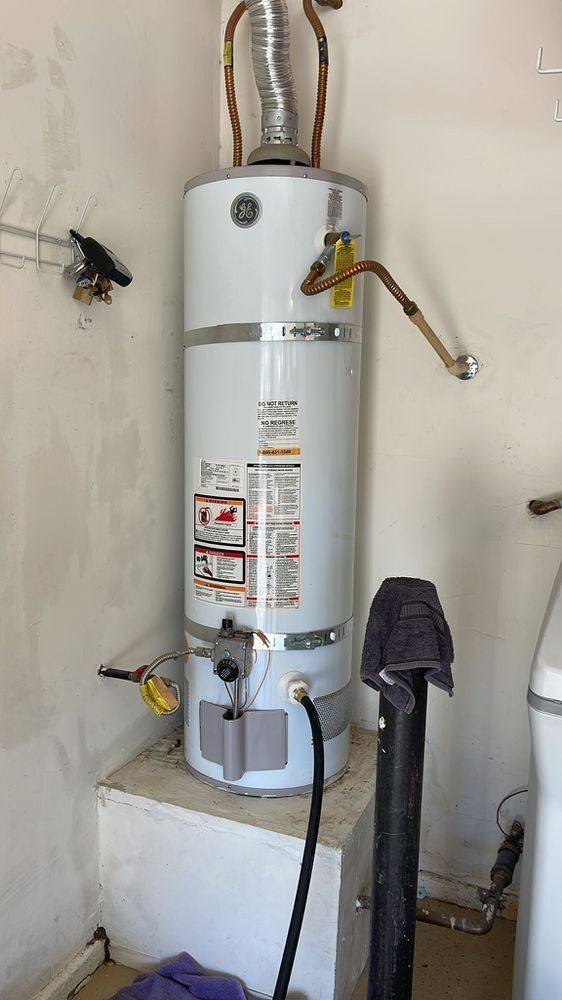 A white water heater is sitting on top of a white box in a room.