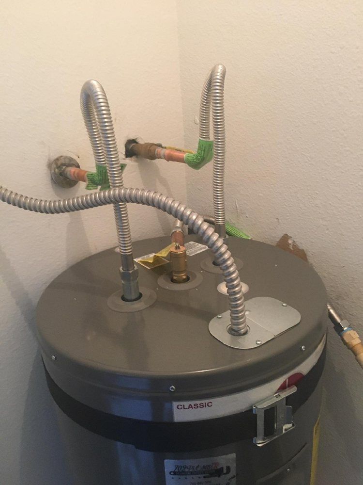 A water heater is sitting in a corner of a room next to a wall.