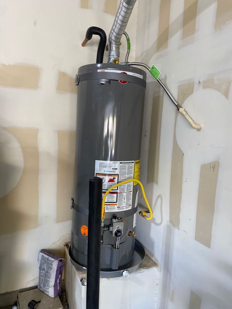A gas water heater is sitting on top of a white box in a room.