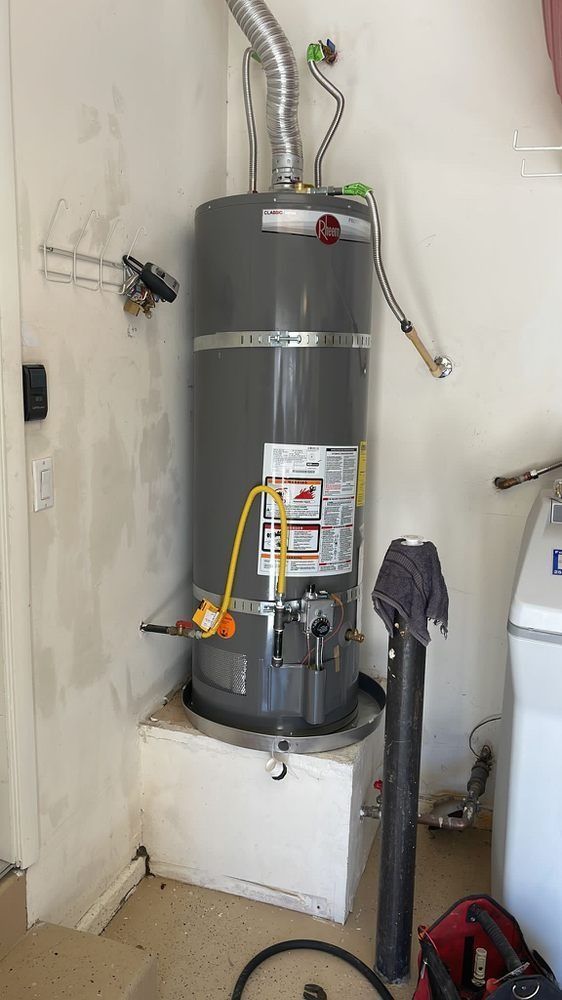 A water heater is sitting in a laundry room next to a washer and dryer.