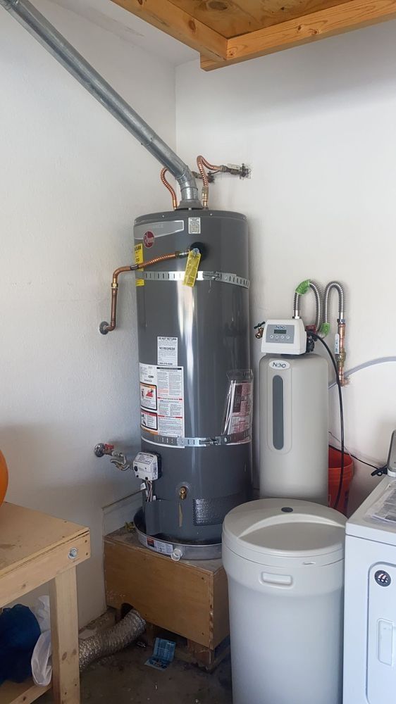 A water heater is sitting in a laundry room next to a washer and dryer.