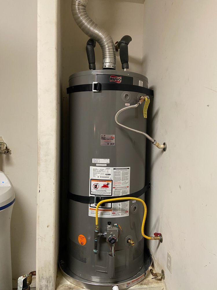 A water heater is sitting in a corner of a room next to a wall.