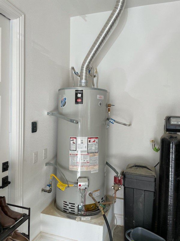 A water heater is sitting in a corner of a room.