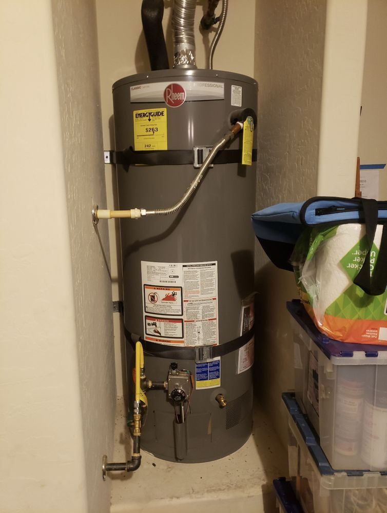 A gray water heater is sitting in a corner of a room.